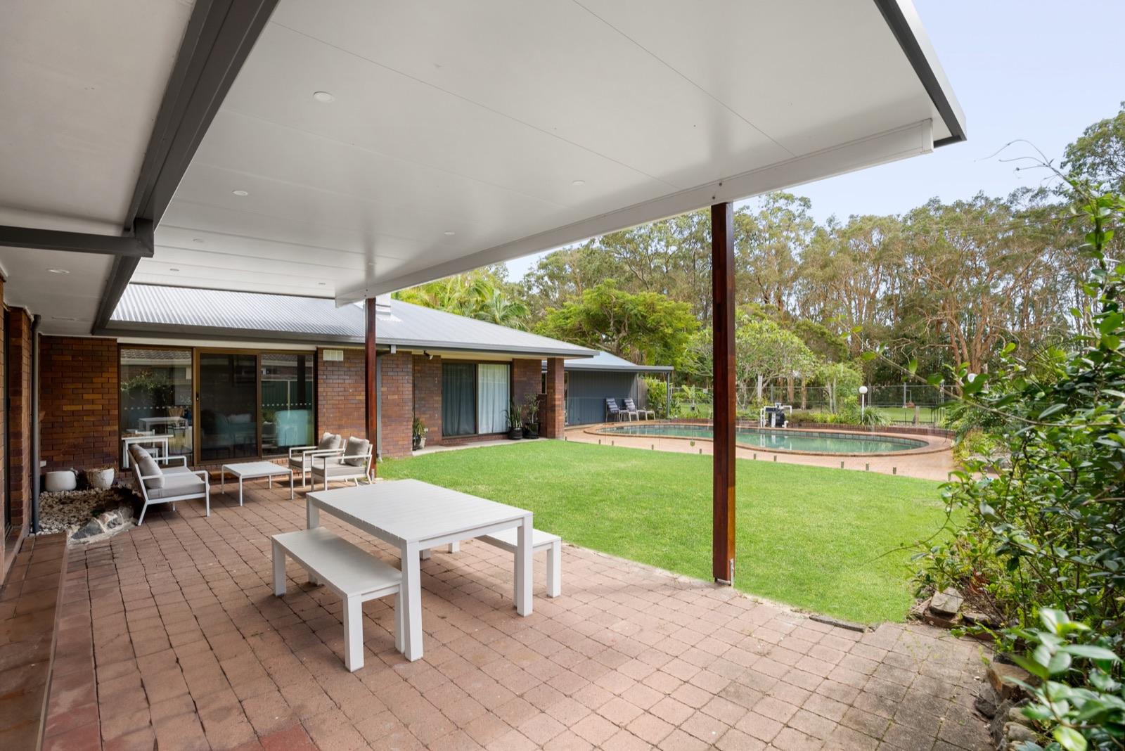 Flyover insulated patio over paved outdoor dining area beside a pool